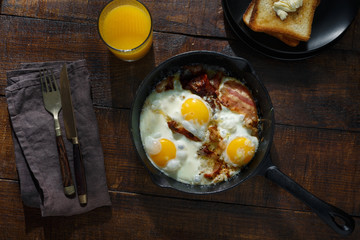 Full breakfast table. Fried eggs with bacon in frying pan