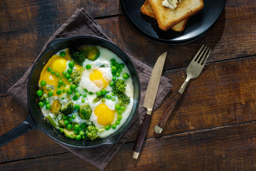 Healthy breakfast. Fried eggs with vegetables in frying pan