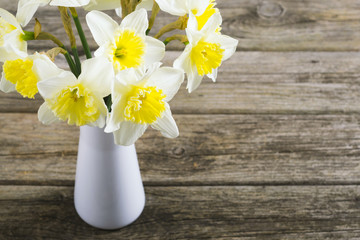 white daffodils at china vase on old weathered wood table