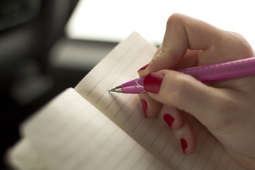 Woman Writing on a Notebook with Pink Pencil