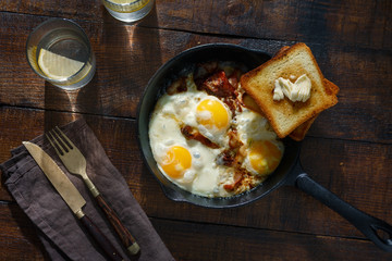 Breakfast table. Fried eggs with bacon in frying pan