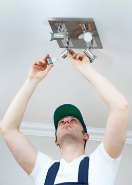 Handsome male electrician changing the light bulb.