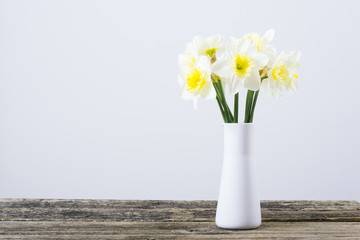 white daffodils at china vase on old weathered wood table