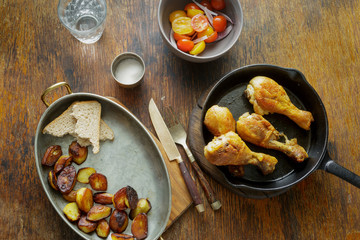 Dinner table. Fried chicken legs pan with potatoes and salad