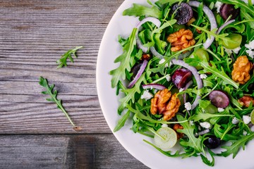 green salad bowl with arugula, walnuts, goat cheese, red onion and grapes