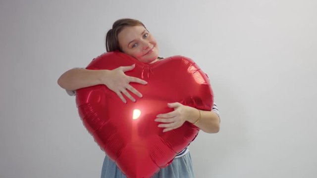 caucasian woman hugs a huge red heart and hold it joying