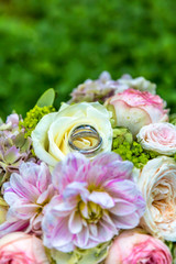 ein wunderschöner Brautstrauß mit zwei Hochzeitsringen auf einer grünen Wiese