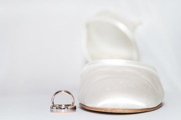 zwei schöne Hochzeitsringe und ein Brautschu vor hellem Hintergrund