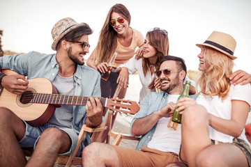 Beautiful young people with guitar having fun on beach.