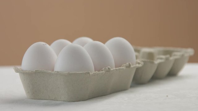 box with white chiken eggs. woman's hand put it on the table and open the box