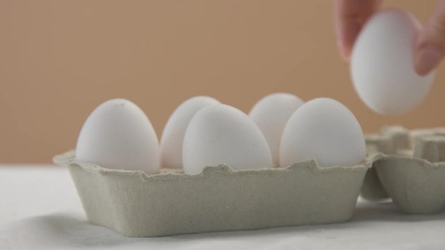 woman's hand put an egg box in perspective open it and take out one white egg