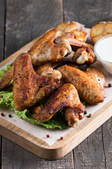 Close-up photo of bbq chicken wings with fries and beer. Barbeques meat with sauces, ketchup, mayonnaise. Fast and junk food concept. 