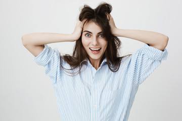 Cheerful and positive girlfriend messing up her hair and smiling brightly at camera, standing over...