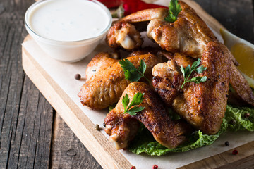 Close-up photo of bbq chicken wings with fries and beer. Barbeques meat with sauces, ketchup, mayonnaise. Fast and junk food concept. 