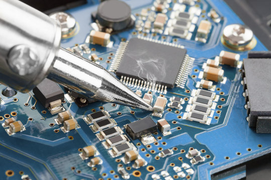 Soldering iron and blue microcircuit - studio shot