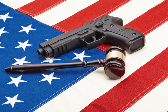 Wooden judge gavel and black color gun over US flag