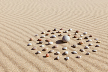 Fototapeta na wymiar pattern of colored pebbles in the shape of a circle on clean sand