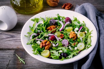 green salad bowl with arugula, walnuts, goat cheese, red onion and grapes