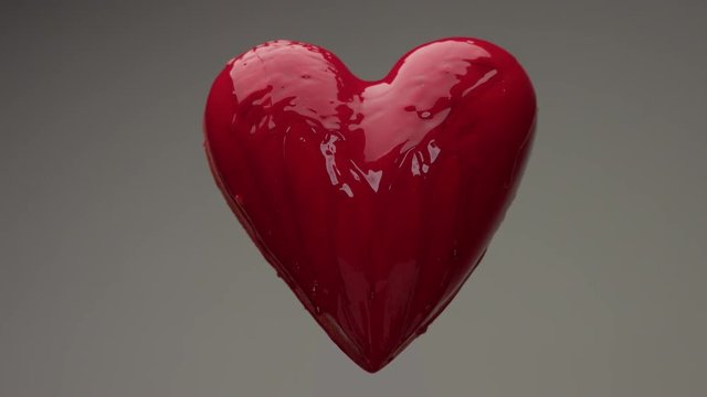 flying red wet heart in air with red transparent liquid covered it and pouring on it. St. Valentine's day heart