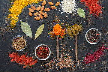 Various colorful spices on a dark background, top view.