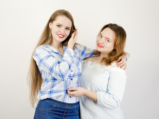 Portrait of two girlfriends girl in casual clothes posing, gray background