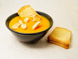 delicious pumpkin pured soup with potatoes and zwiebacks bread slices. for vegetarian, vegan and healthy concept