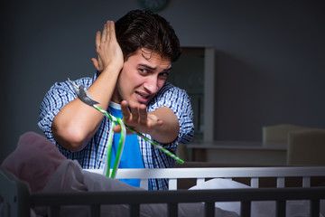 Obraz premium Young father under stress due to baby crying at night