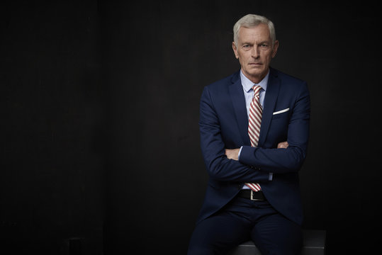 Confident businessman portrait. Executive senior lawyer businessman wearing suit and looking at camera while standing at isolated black background with copy space. 