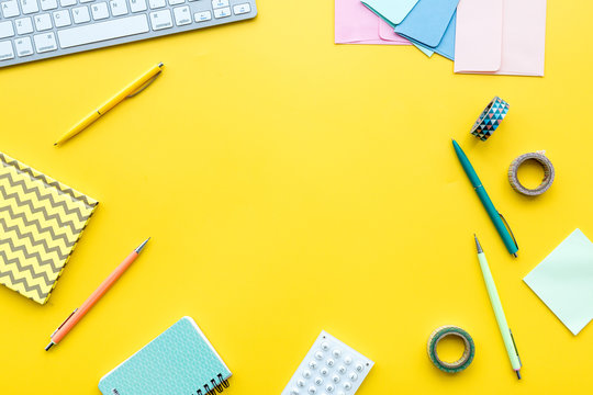 Scattered stationery near keyboard on student's desk. Yellow background top view copy space