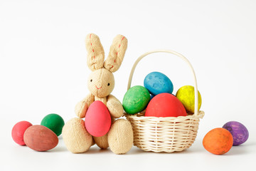 Rabbit doll with Easter eggs in basket isolated on white background.