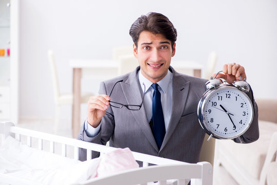 Young businessman trying to work from home caring after newborn 