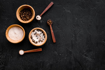 Cosmetics for skin care and relaxation. Chocolate brown spa salt on black background top view copy space