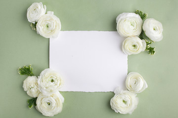 Obraz na płótnie Canvas Floral frame made of white flowers and leaves on green background. Floral background. Flat lay, top view.