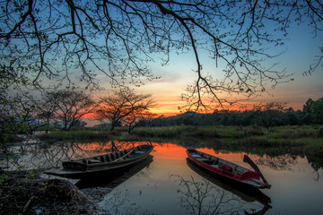 Beautiful sunset at the mouth of the river with the shadow of fishing boats and big trees..