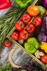 Set of different fresh raw vegetables in the wooden tray, light background
