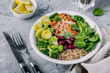 Healthy buddha bowl lunch with grilled chicken, quinoa, spinach, avocado, brussels sprouts, broccoli, red beans with sesame seeds