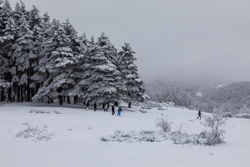 Family playing in the snow in front of the hermitage of Hontanares in Riaza, Segovia