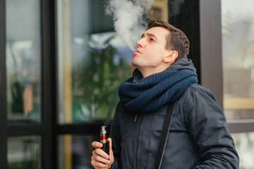 Vaping. Young men vaping an electronic cigarette. Vaping outdoors. Safe smoking. Young vaper.