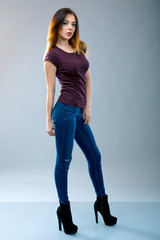 full-length portrait of young girl on grey background. redhead Woman dressed in jeans and heels