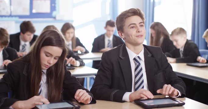 4k, Secondary school students using digital touchscreen tablet in a classroom.
