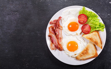 plate of fried eggs with bacon and vegetables