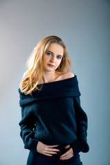 Fototapeta premium Portrait of charming young lady posing in black pullover with bare shoulders over grey background
