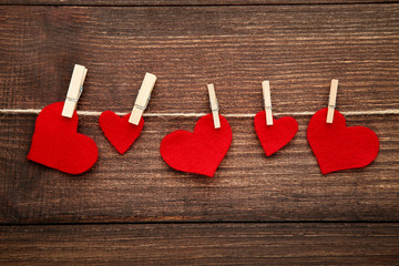 Red hearts hanging on rope on brown wooden background