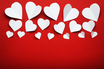 White paper hearts on red background
