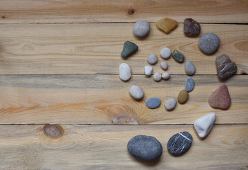 spiral of natural sea stones lined on a wooden background. stone therapy. spa salon.
