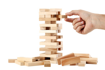 Male hand playing wooden blocks tower game on white background