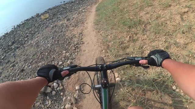 Fat bike also called fatbike or fat-tire bike in summer riding. Driving on different surfaces of stones, sand, grass, mud. A view from the first person to the steering wheel, hands and road.
