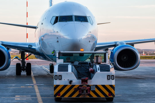 Tow tractor pushes the passenger aircraft at the airport apron