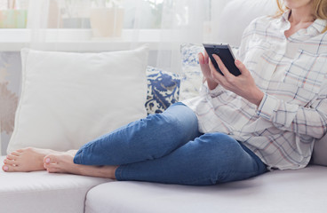 Woman at home relaxing reading on the smartphone 