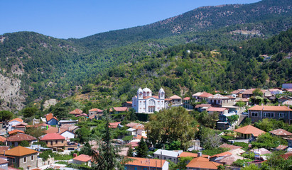 Fototapeta na wymiar Mountain Village Pedoulas, Cyprus. View over roofs of houses, mountains and Big church of Holy Cross. Village is one of most picturesque villages of Troodos mountain range